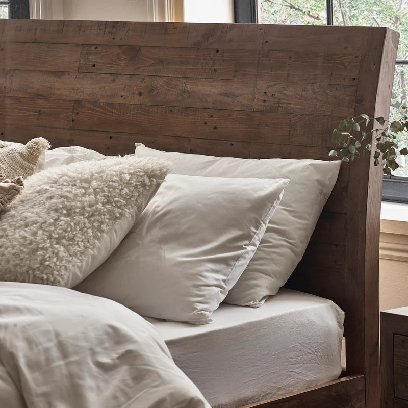 Bed with wooden headboard and pillows in a bedroom setting