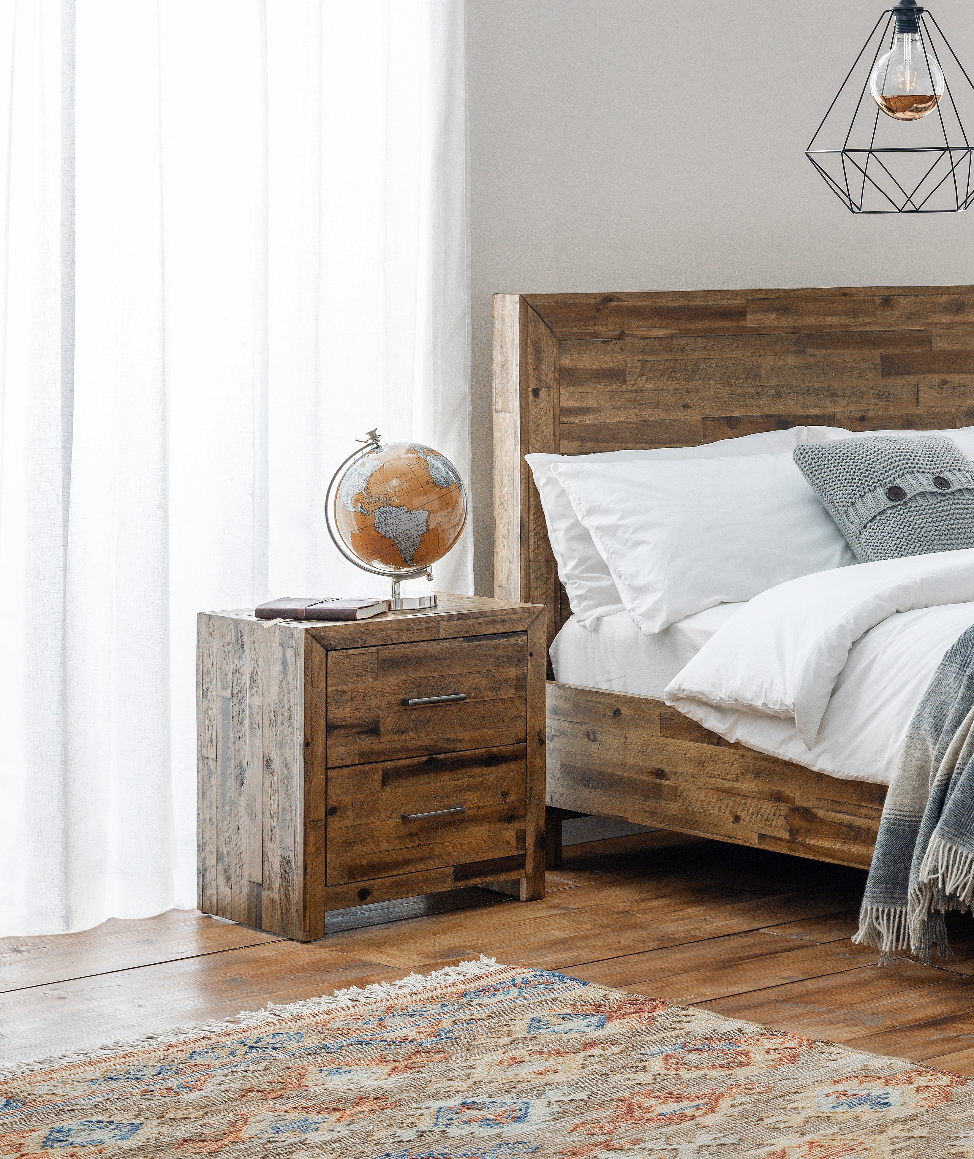 Wooden bed and nightstand with a globe in a bedroom setting