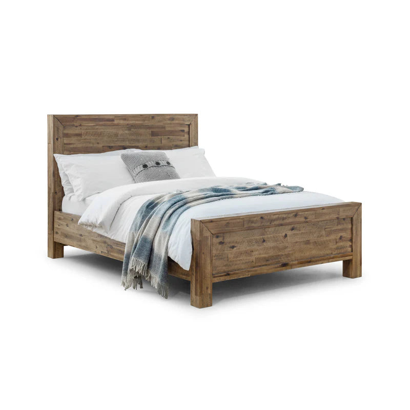 Wooden bed with white bedding and a gray blanket on a white background