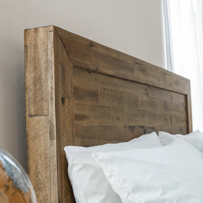 Wooden headboard with white pillows against a neutral wall