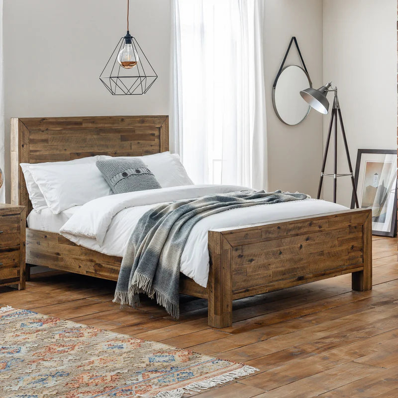 Wooden bed in a bedroom with a rug and lamp
