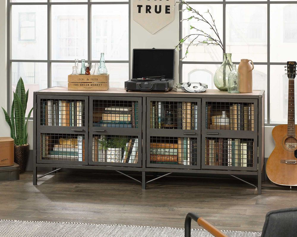 Gray industrial-style entertainment console with decorative items in a room with large windows.