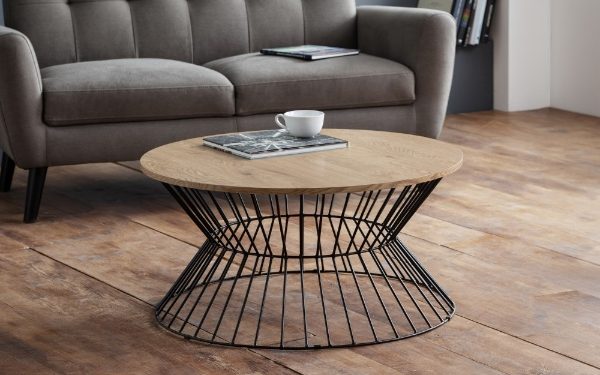 Round wooden coffee table with black metal base in a living room setting.