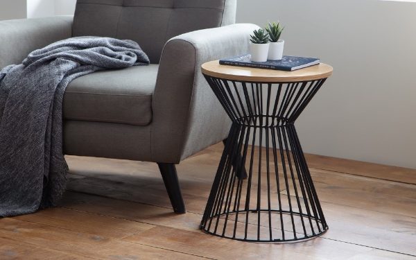 Small side table with black metal base and wooden top next to a gray sofa.