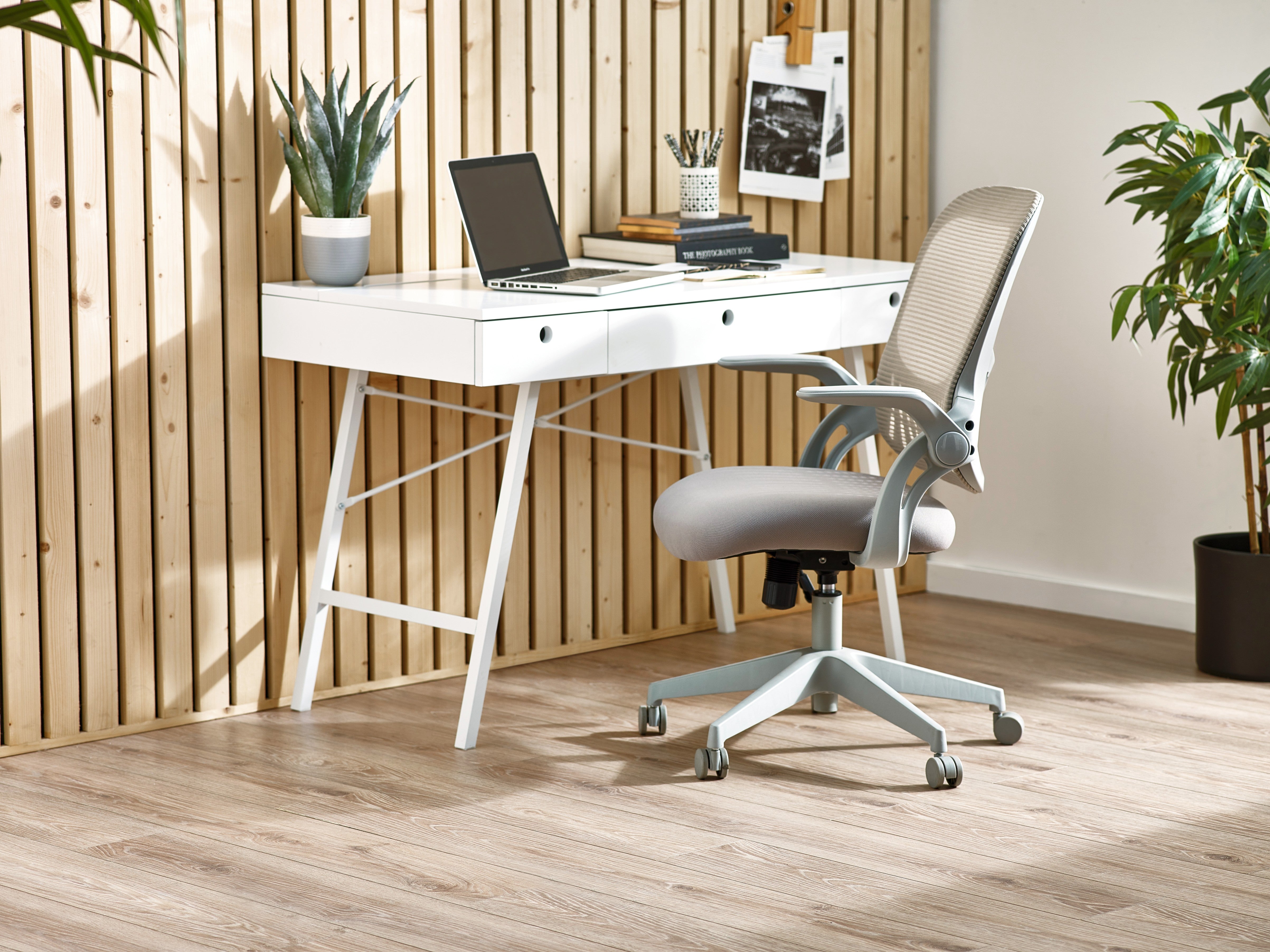 White desk with a laptop and office chair in a room with wooden floor and wall.