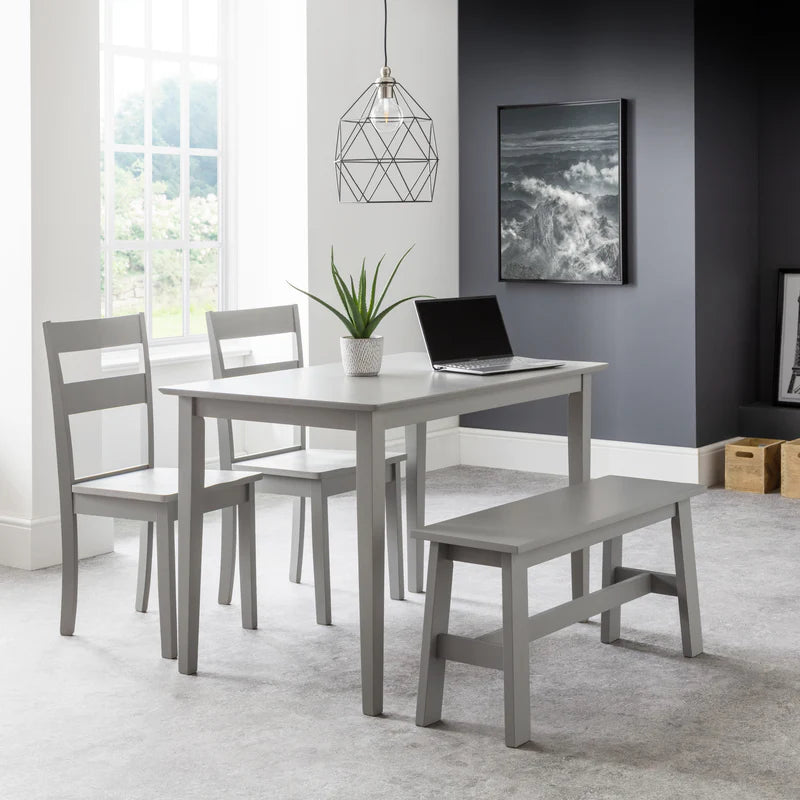 Gray dining set with table, chairs, and bench in a room with a window and wall art.