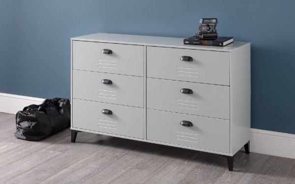 White dresser with multiple drawers against a blue wall.