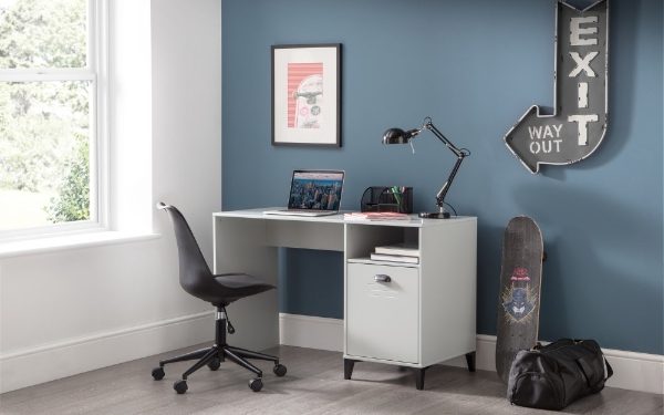 Home office with a desk, chair, laptop, and decorative items against a blue wall.