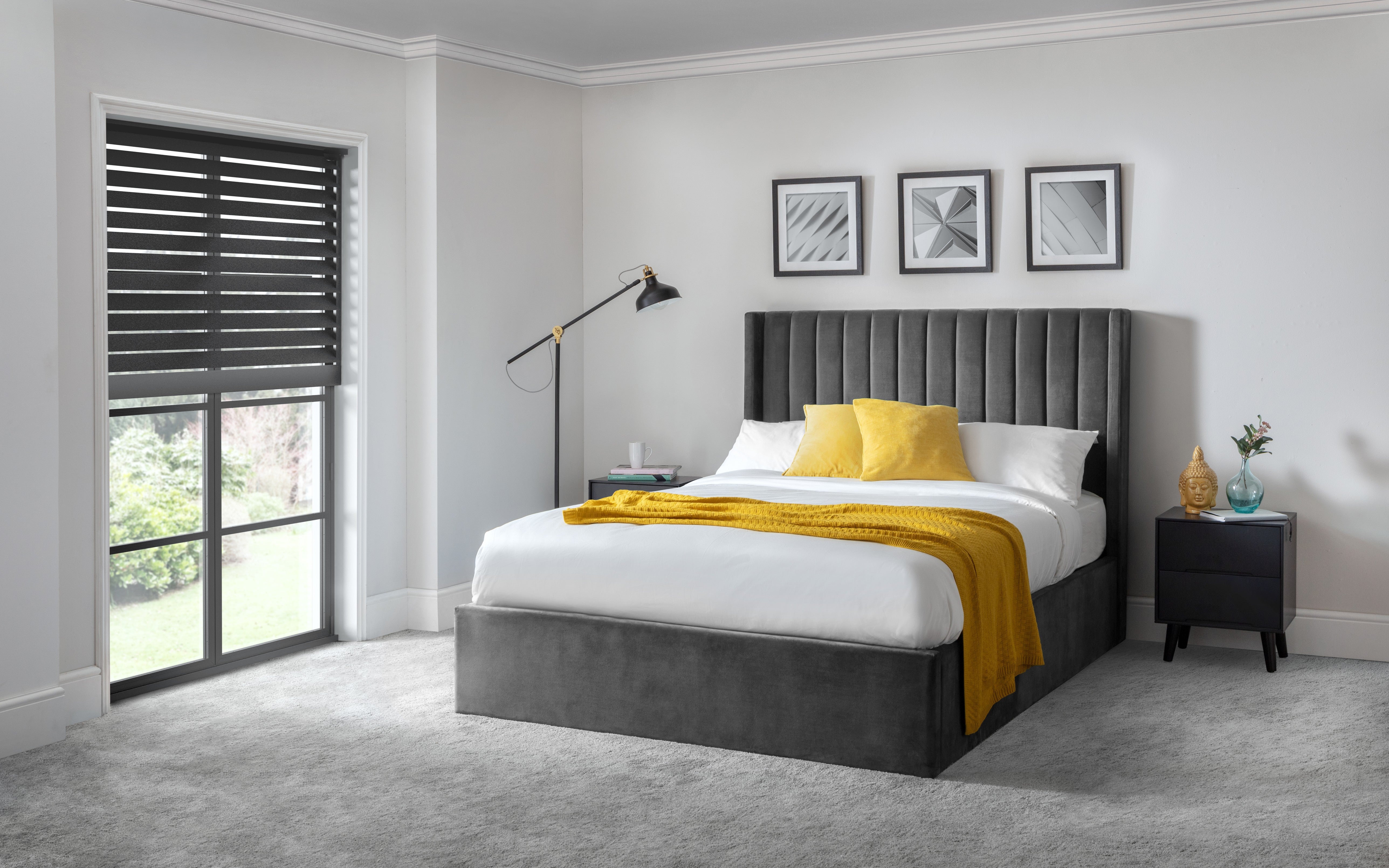 Modern bedroom with gray upholstered bed, yellow pillows, and decor.
