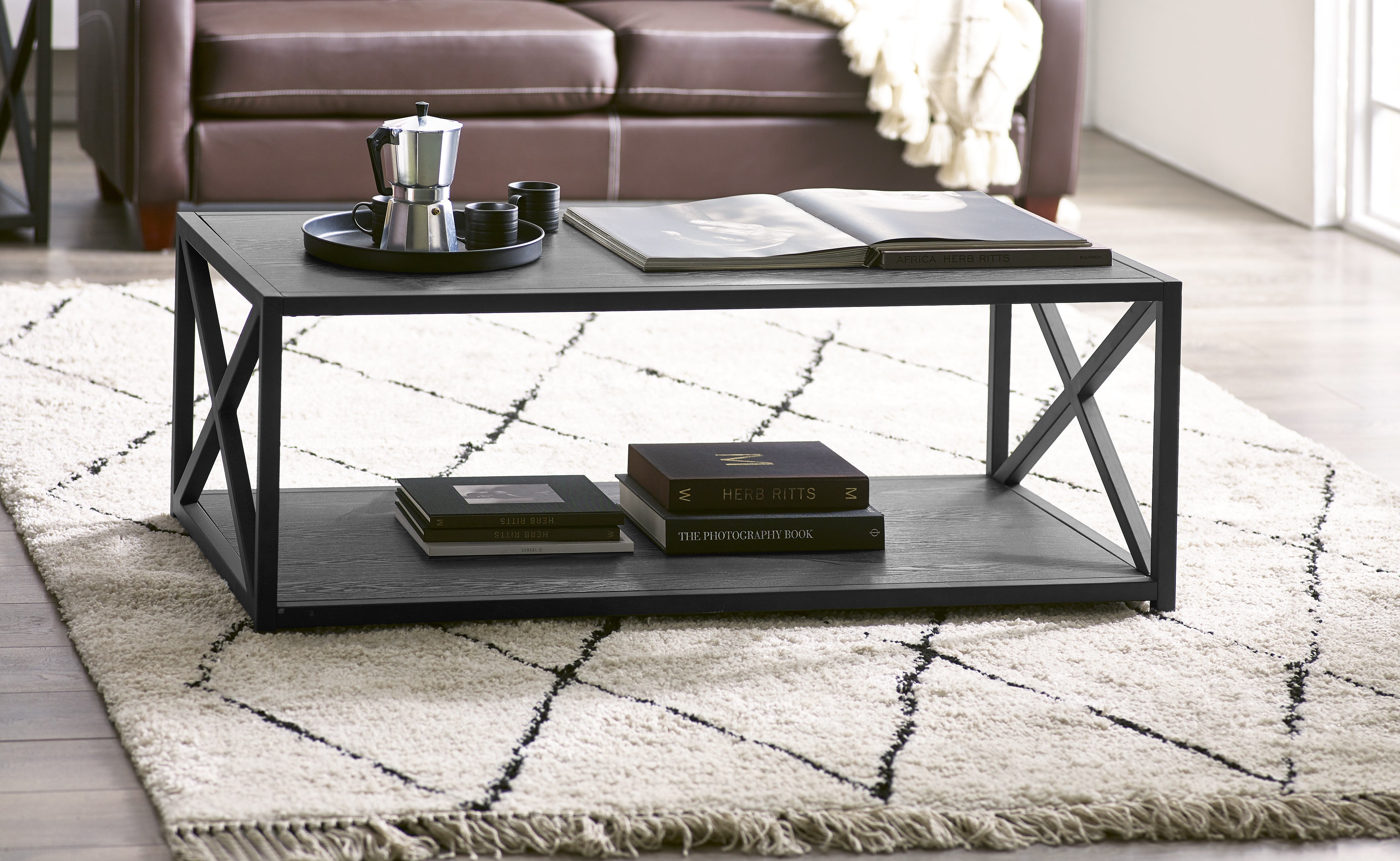 Black metal coffee table with books and a tray in a living room setting