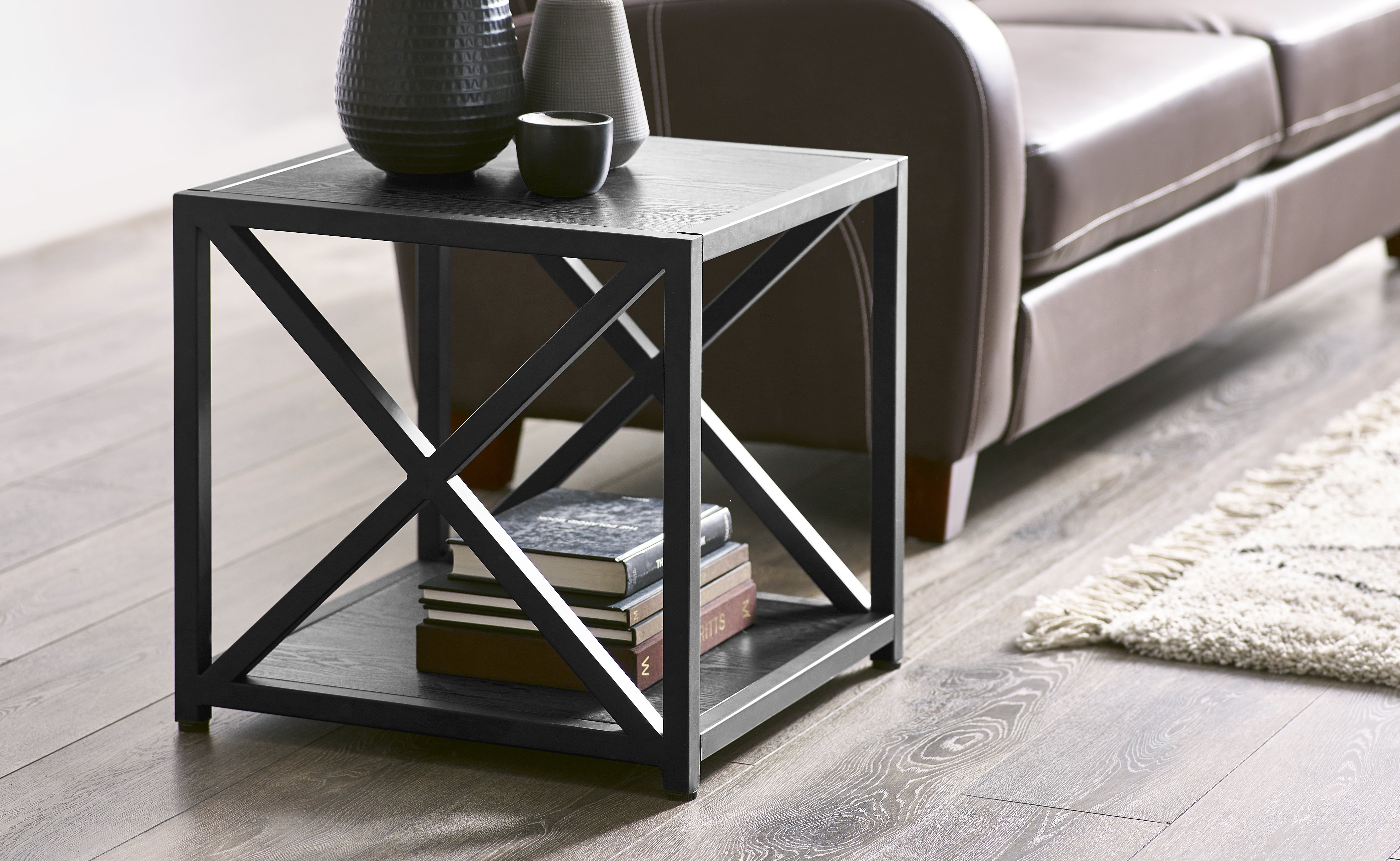 Black metal side table with books and decorative items in a living room setting.
