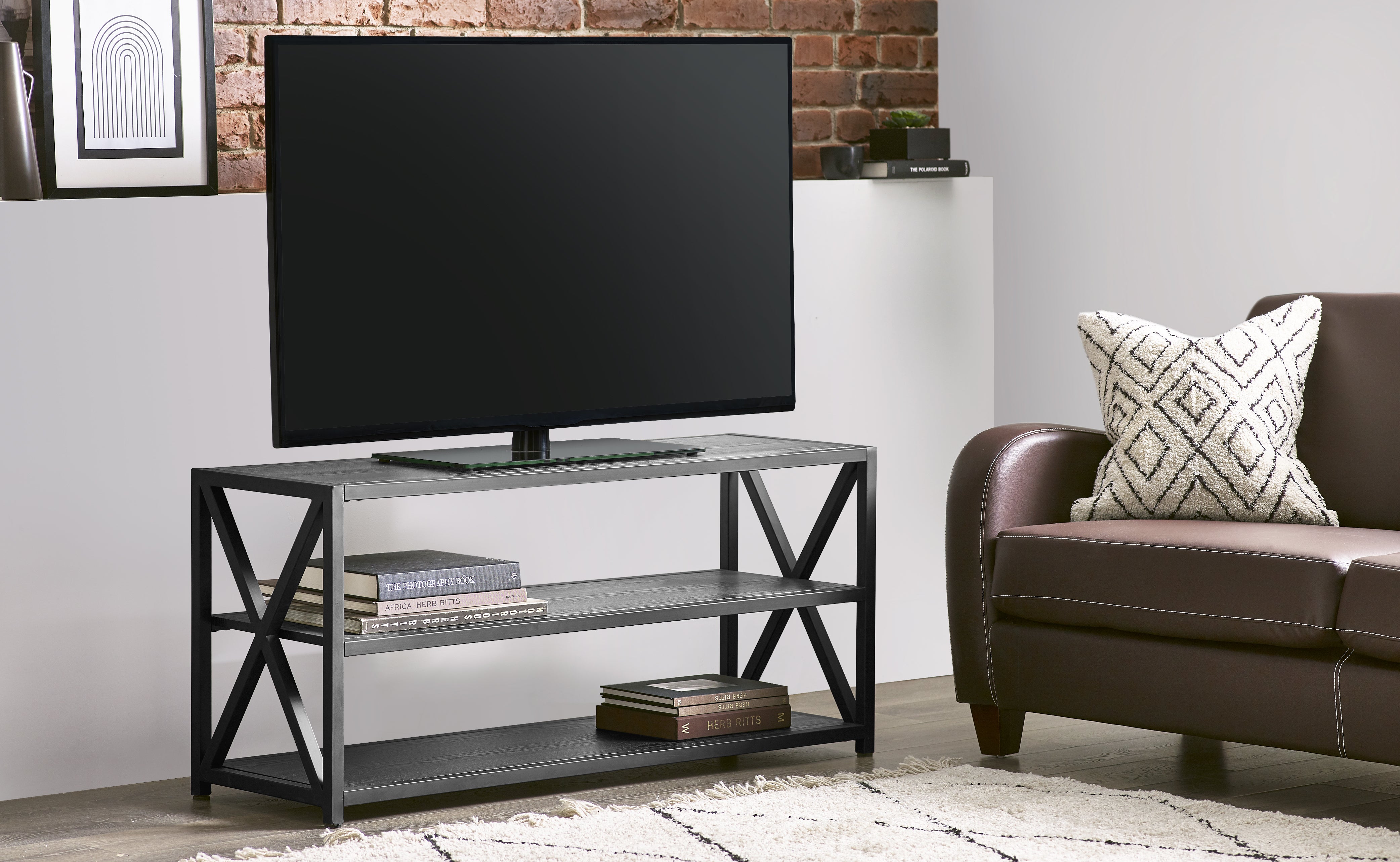 Modern living room with a TV on a metal stand and a brown sofa.