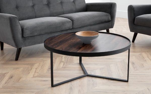 Round wooden coffee table with metal legs in a living room setting.