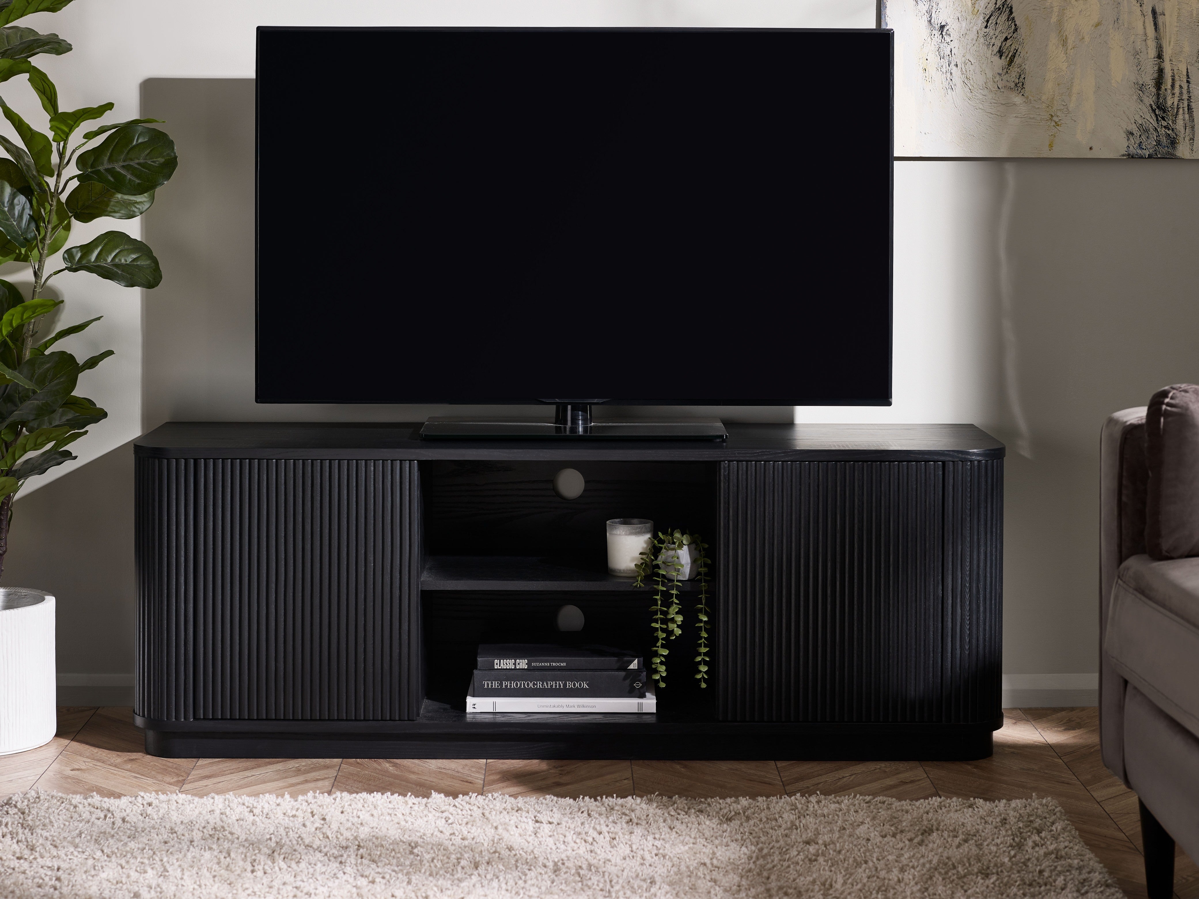 Black TV stand with a television in a living room setting