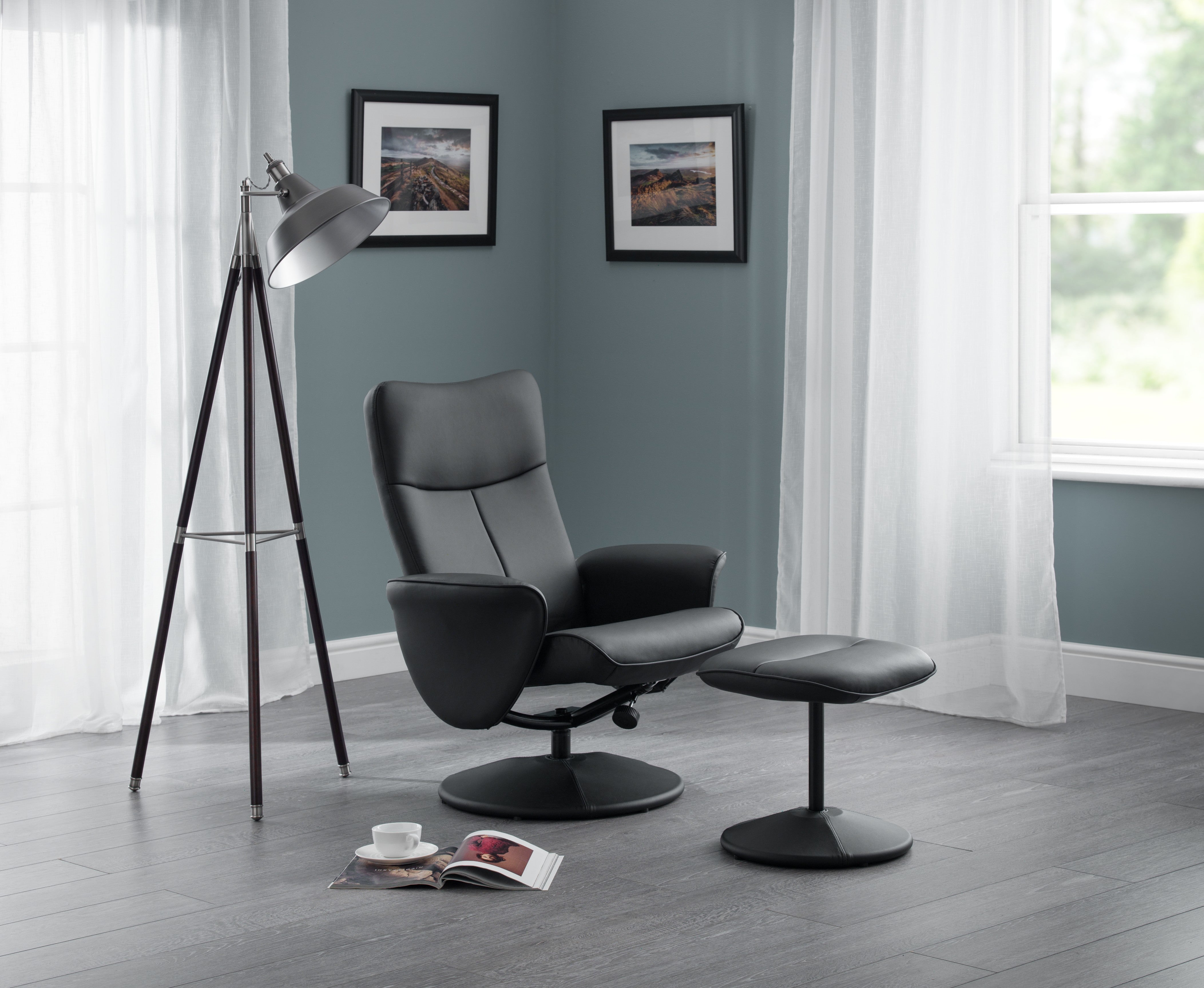 Modern black leather armchair with ottoman in a room with gray walls and white curtains.