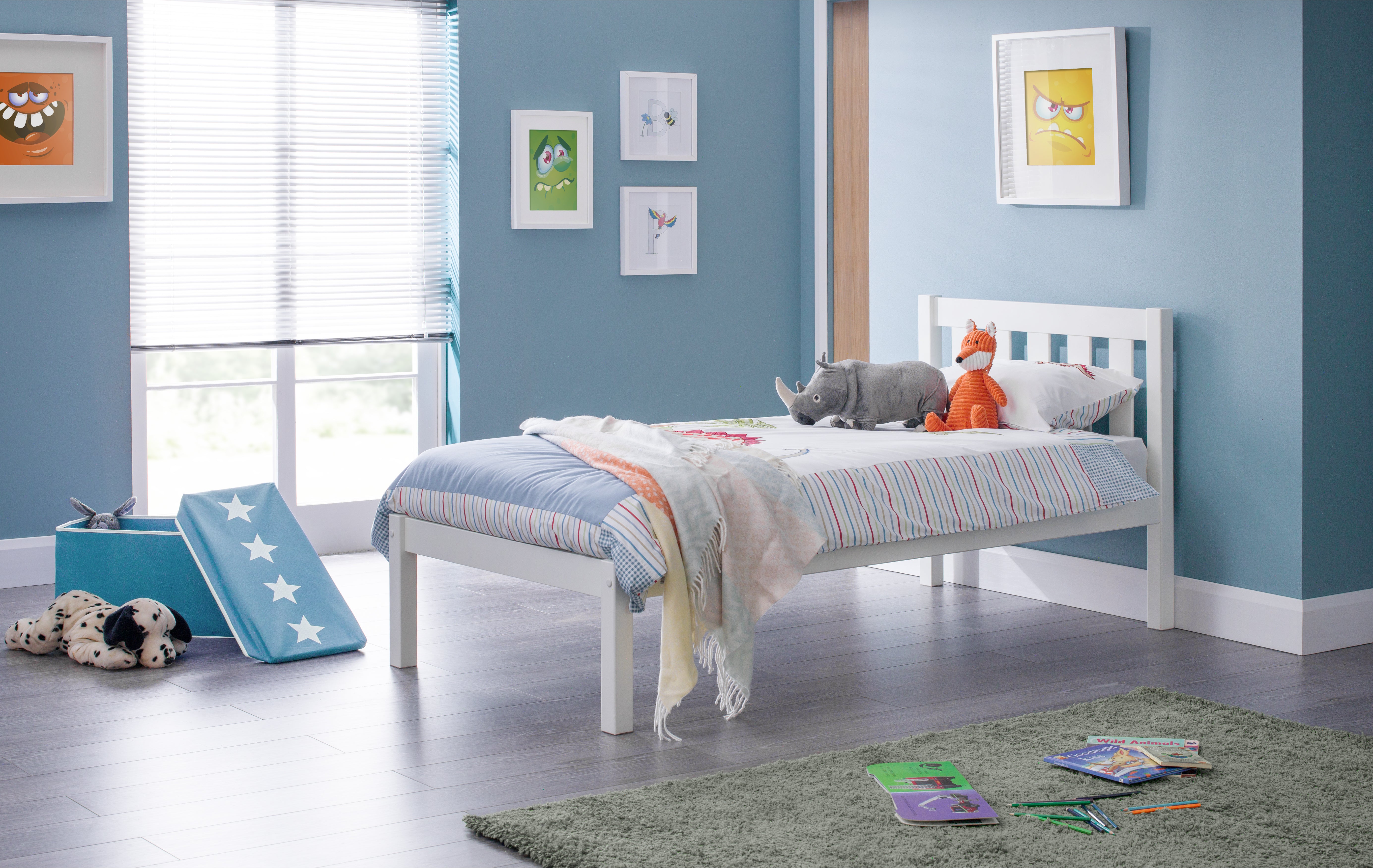 Children's bedroom with a white bed, colorful bedding, and toys on a gray floor.