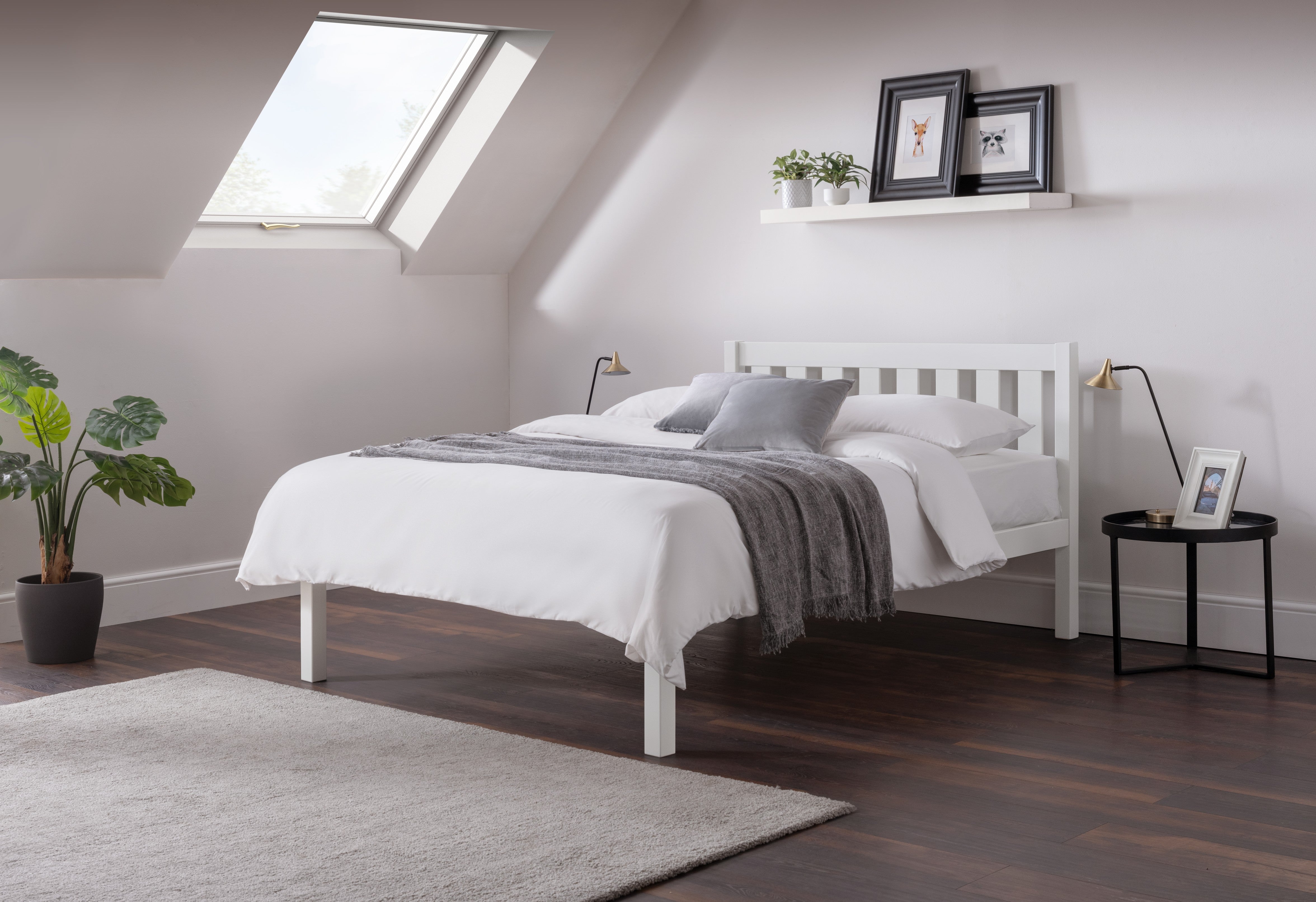 Modern bedroom with a white bed, wooden floor, and skylight.