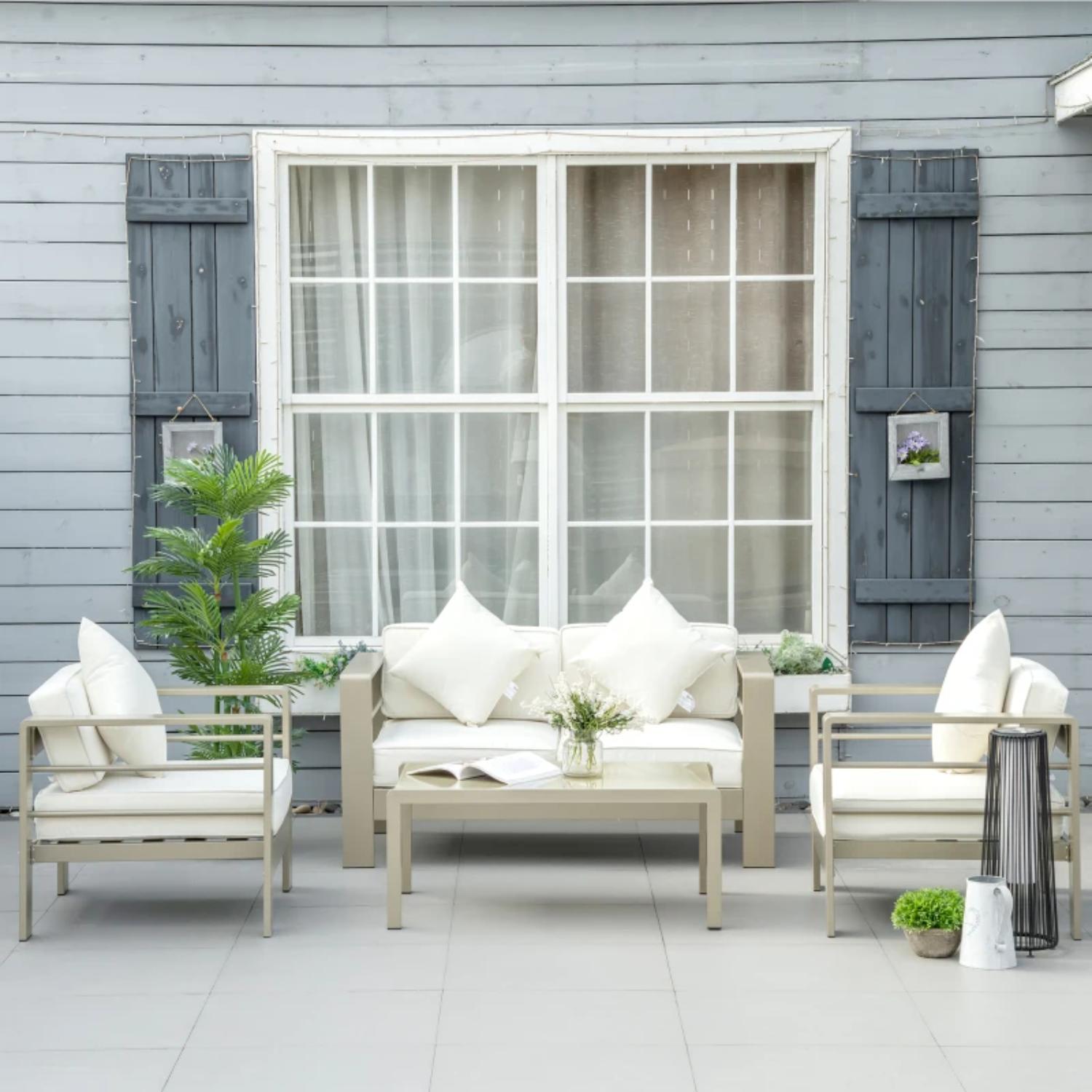 Outdoor patio set with white furniture against a gray house background