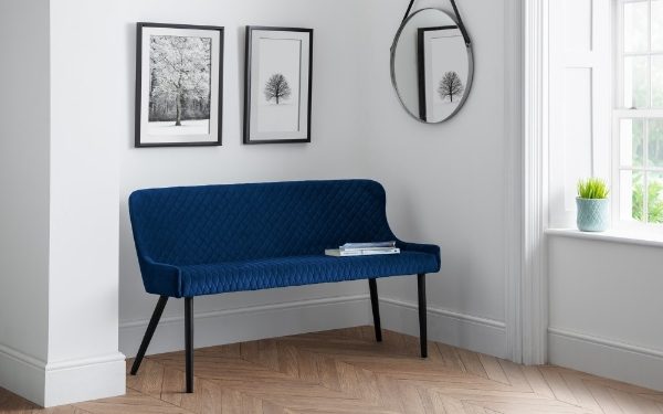 Blue bench in a room with framed pictures on the wall and a window.