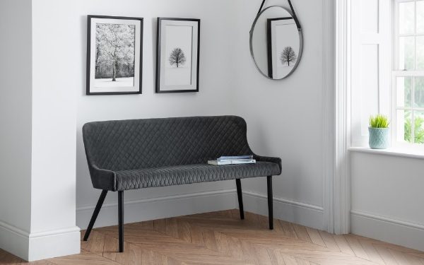 Black quilted bench in a room with framed pictures on the wall.