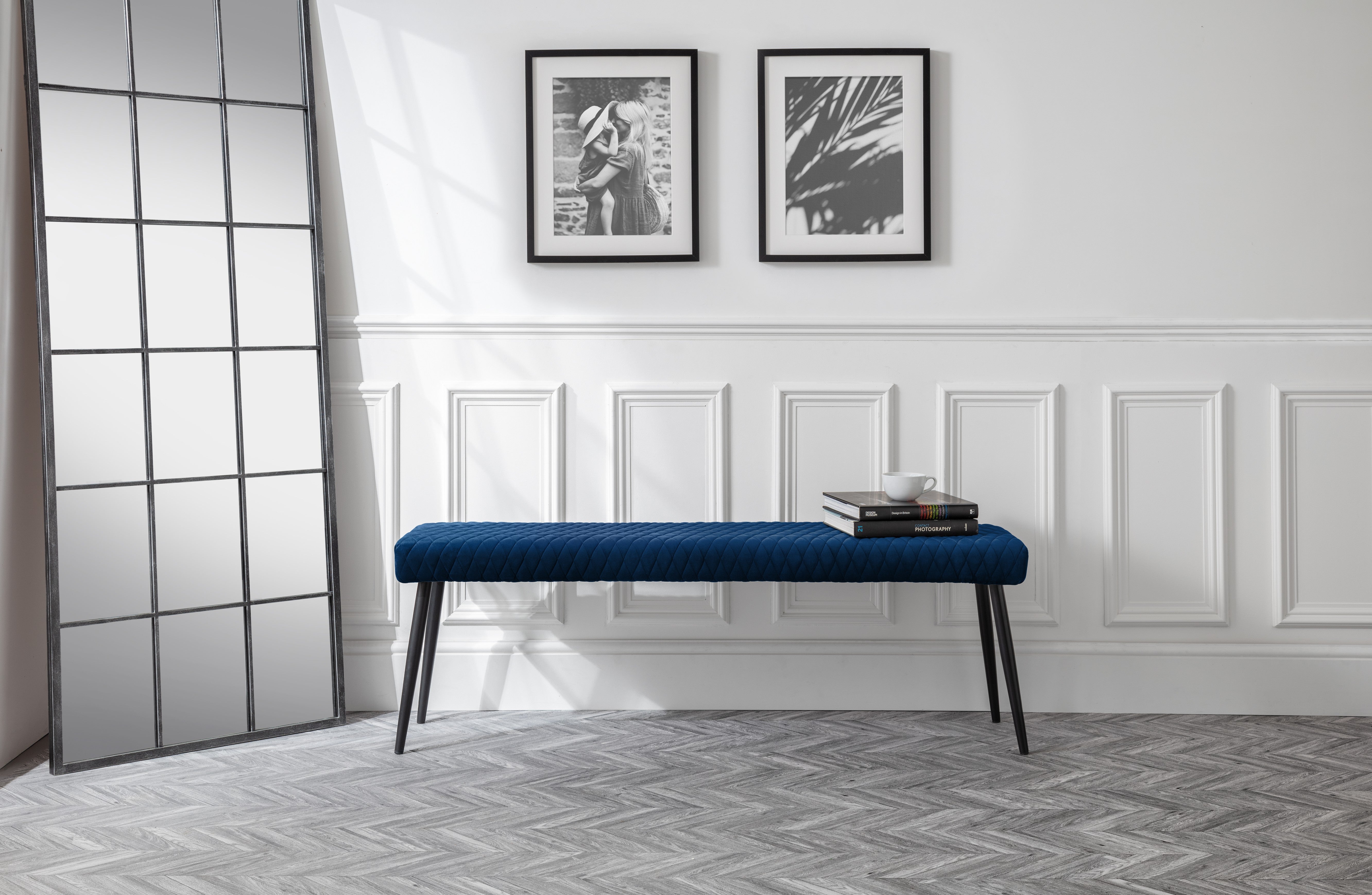Blue bench in a room with white walls, framed pictures, and a glass partition.