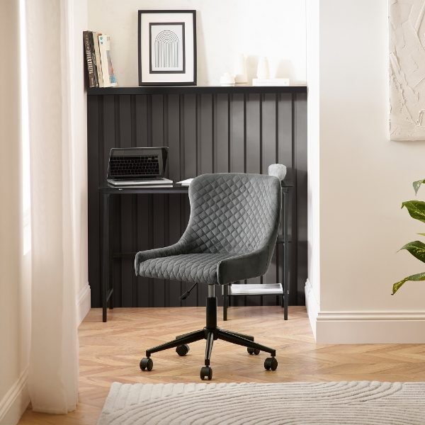 Gray office chair in front of a black desk with a laptop in a home office setting.