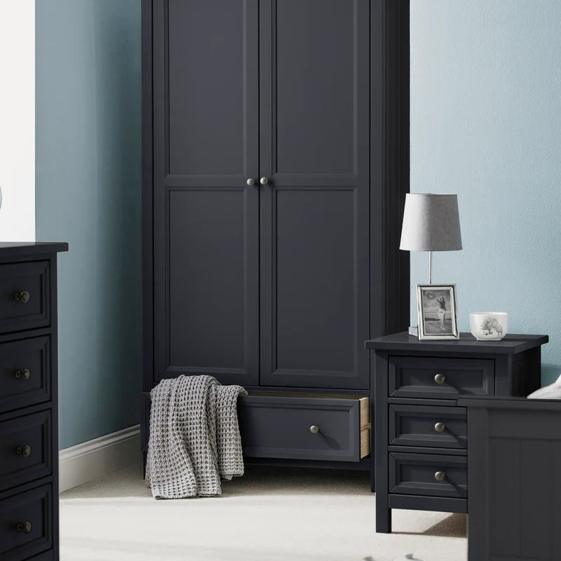 Dark gray wardrobe and matching nightstand with a lamp and photo frame in a bedroom setting.
