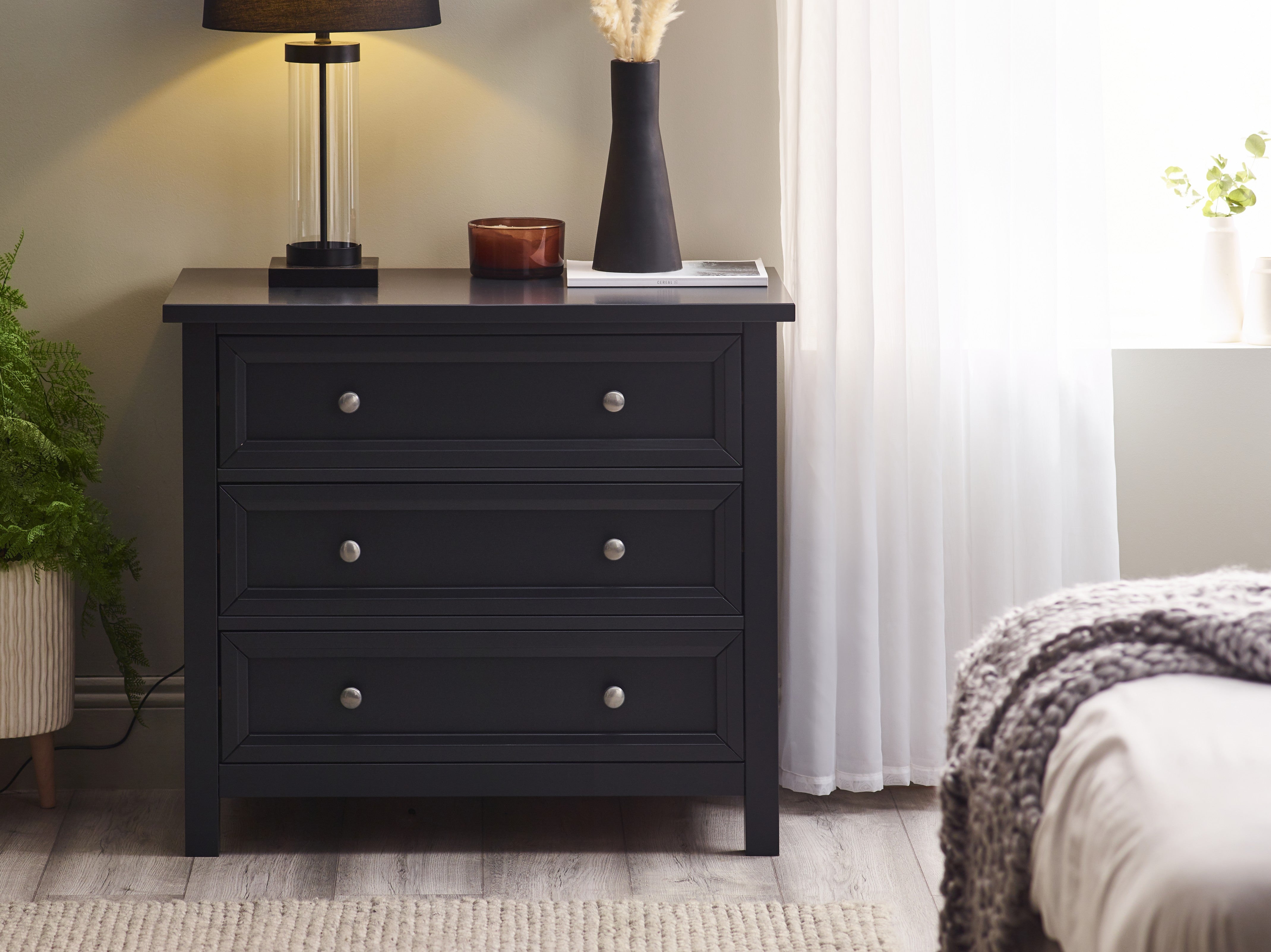 Black dresser with decorative items in a bedroom setting