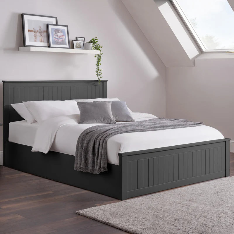 Bedroom with a black bed frame, white bedding, and gray throw blanket.