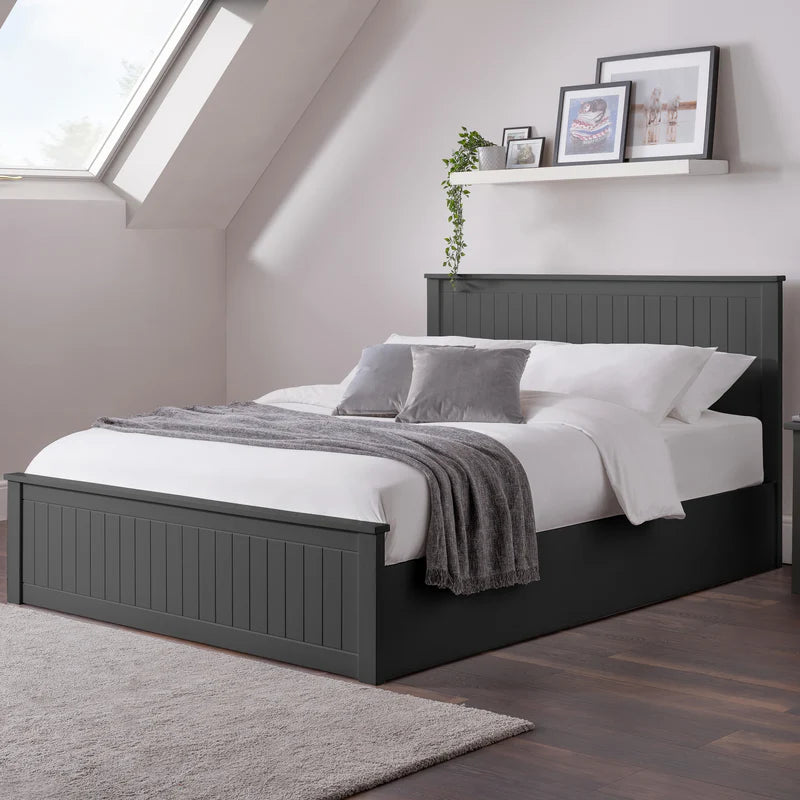 Black bed frame with white bedding and gray throw in a bedroom setting.