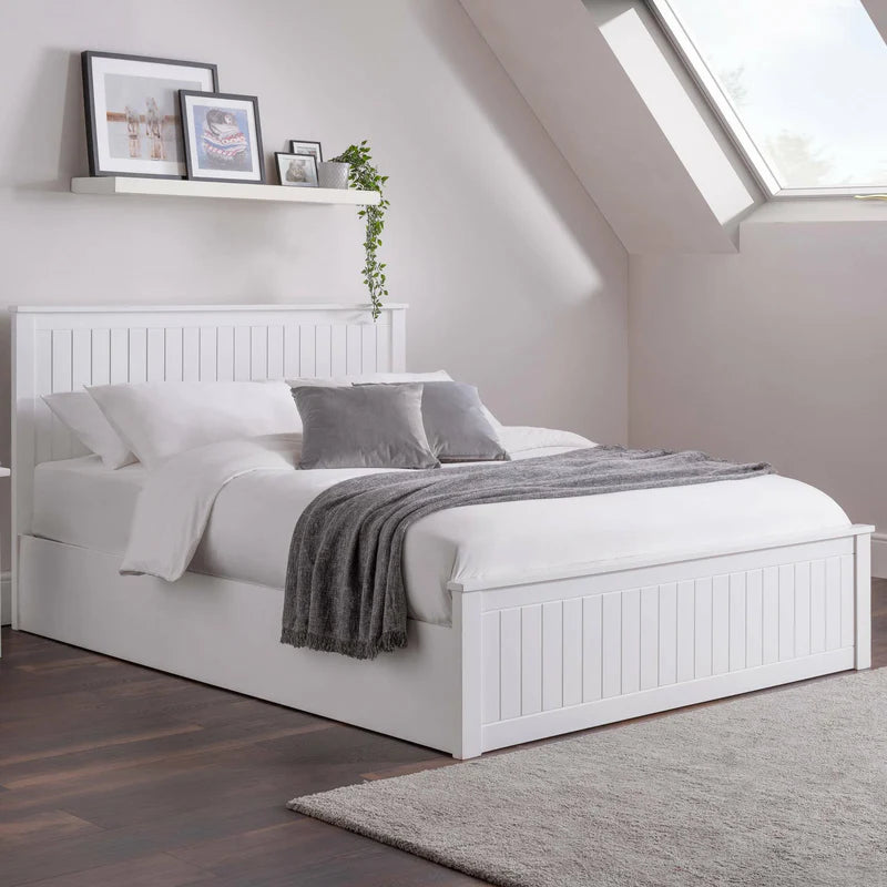 White bed with gray bedding in a bedroom with a skylight.