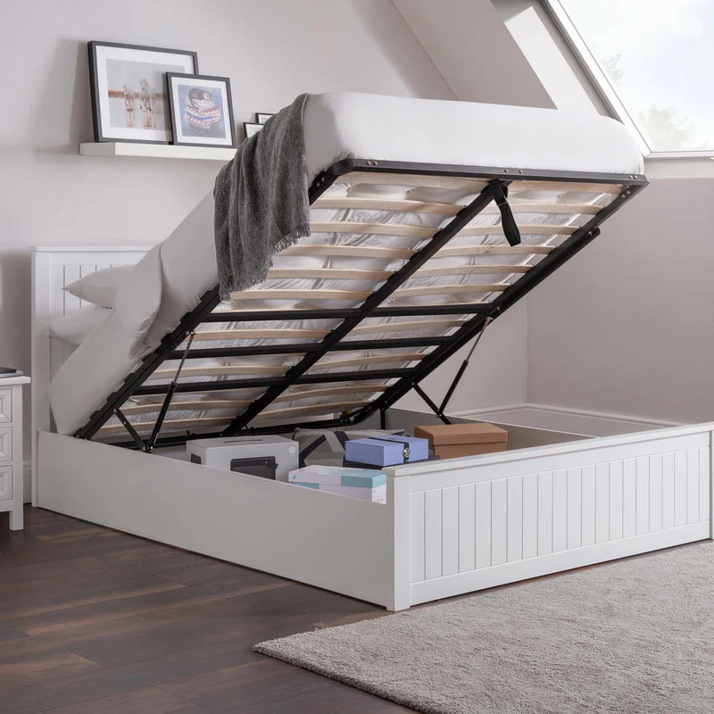 White bed with raised storage compartment in a room with a skylight.