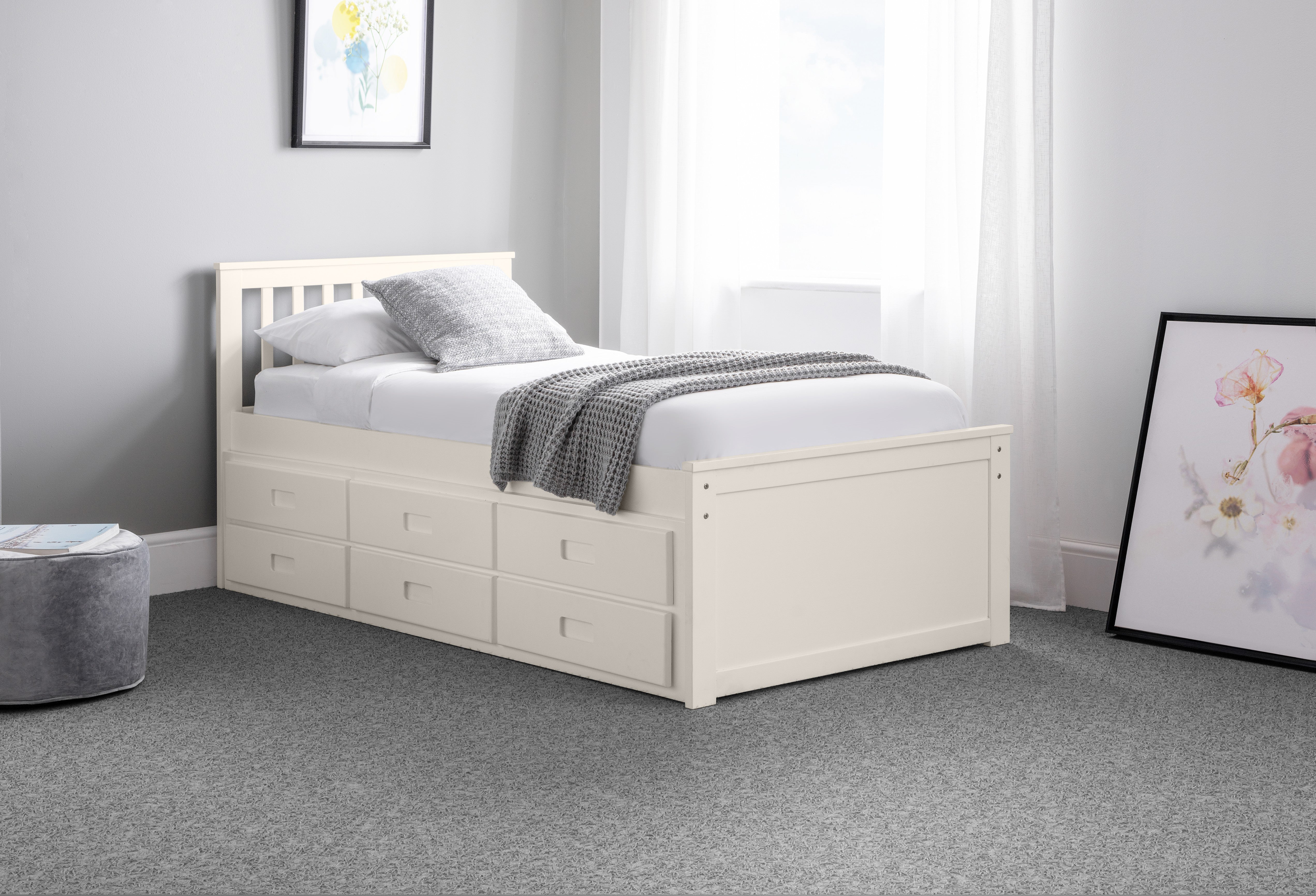 White wooden bed with storage drawers in a bedroom setting.