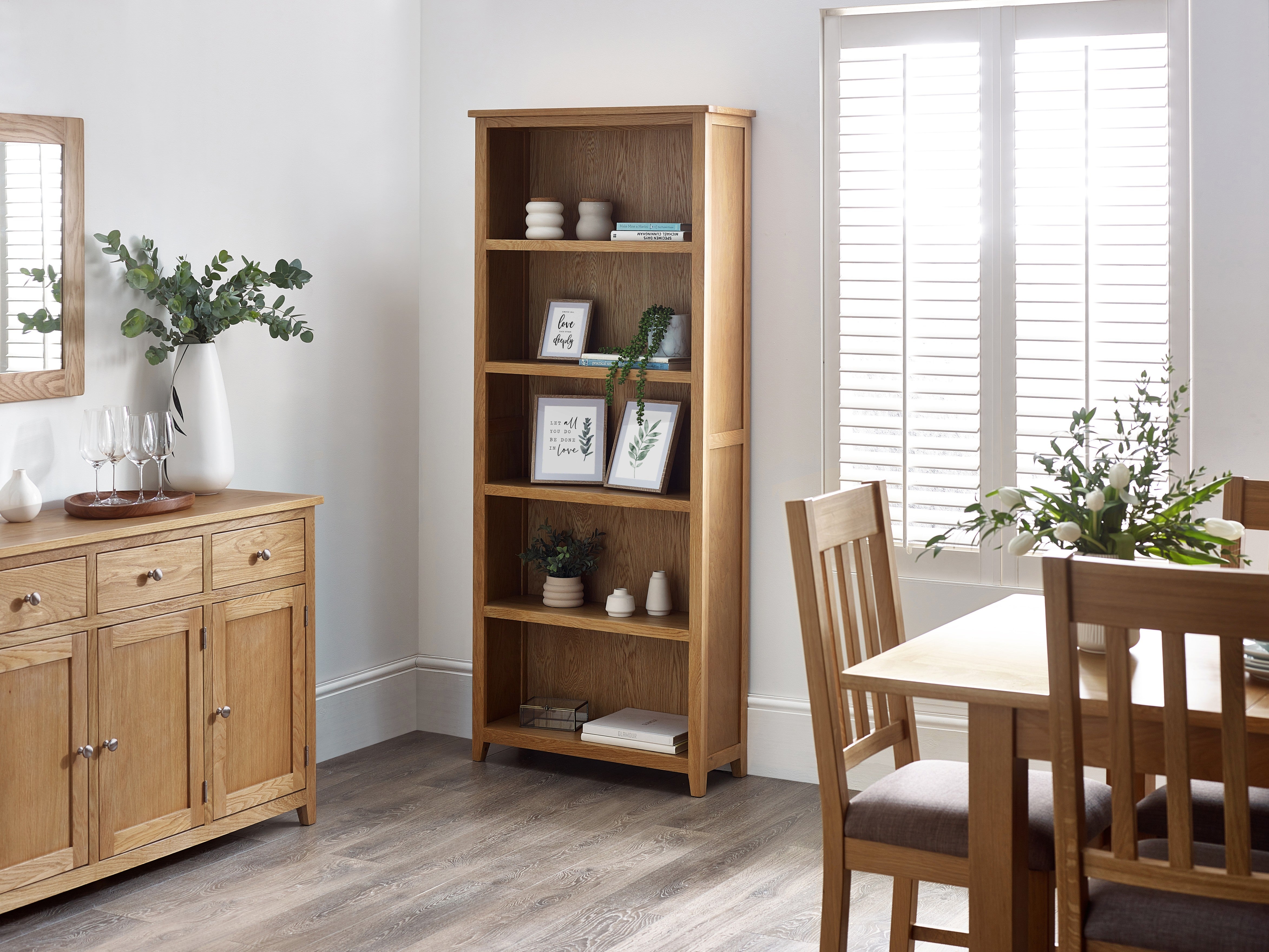 Wooden bookshelf and dining set in a room with a window and mirror.