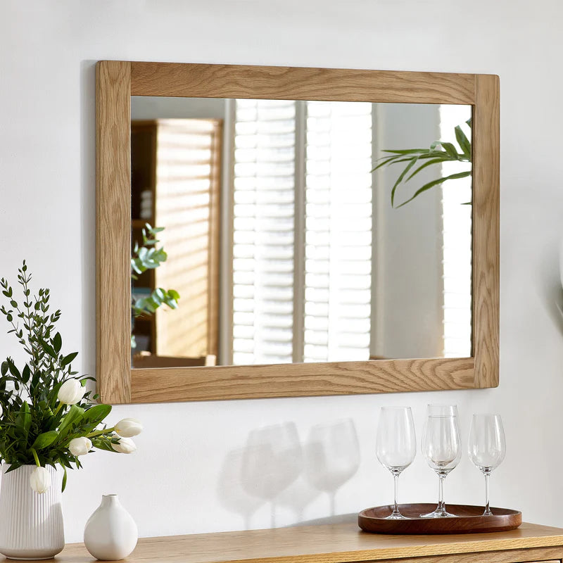 Wooden-framed mirror on a wall with decor items below