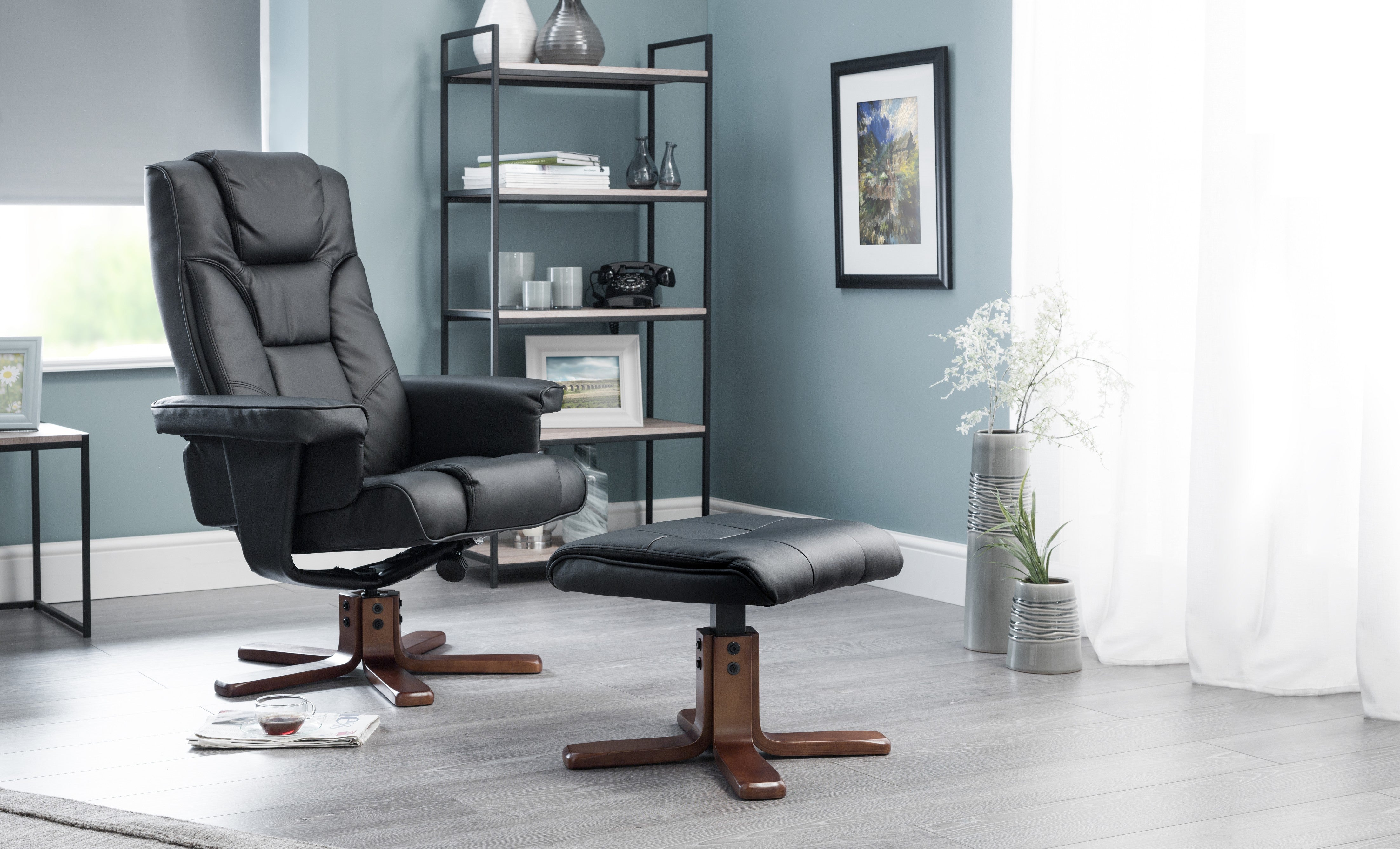 Black recliner chair with ottoman in a room with a bookshelf and decor.