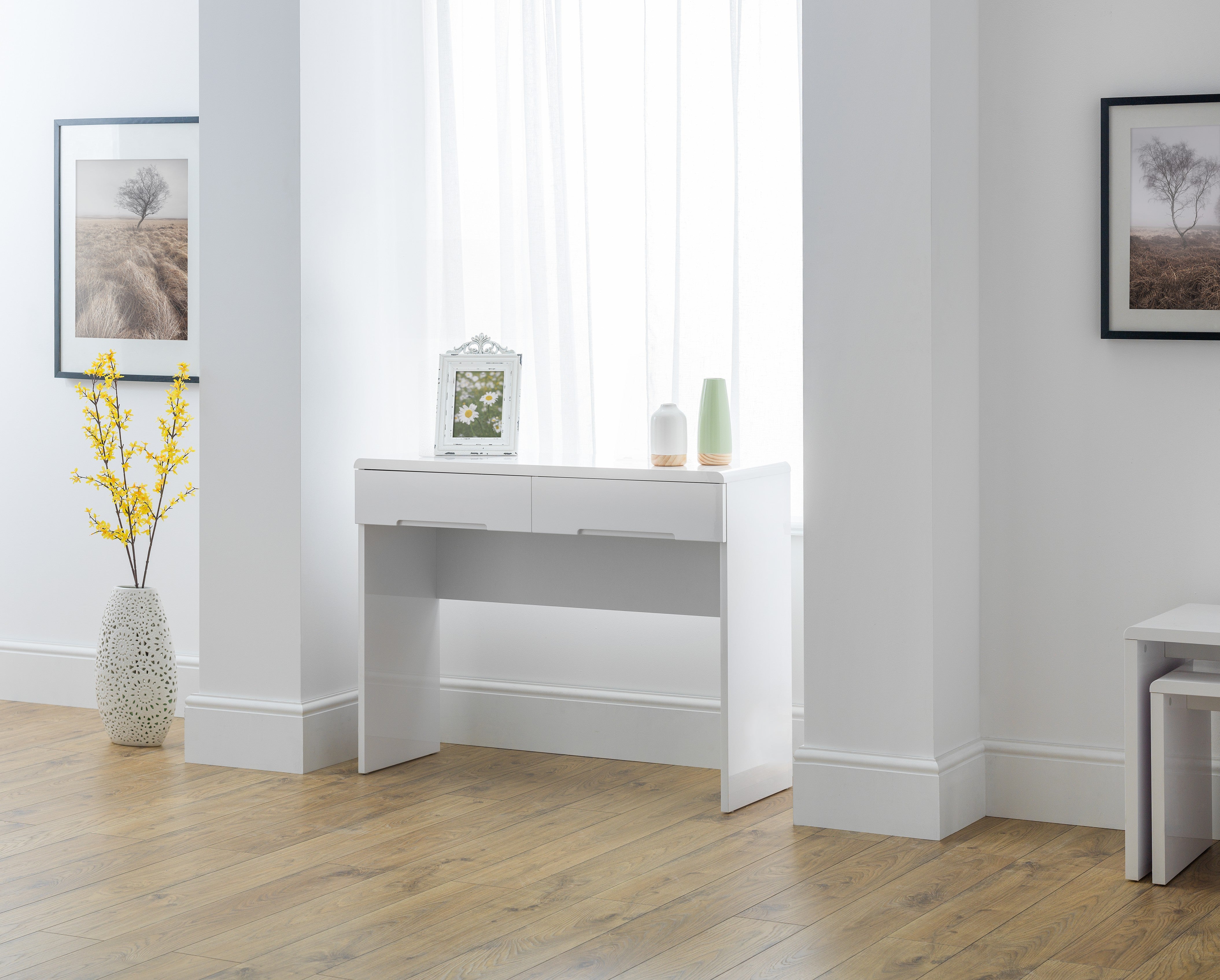 White desk in a room with light wood flooring and white walls.