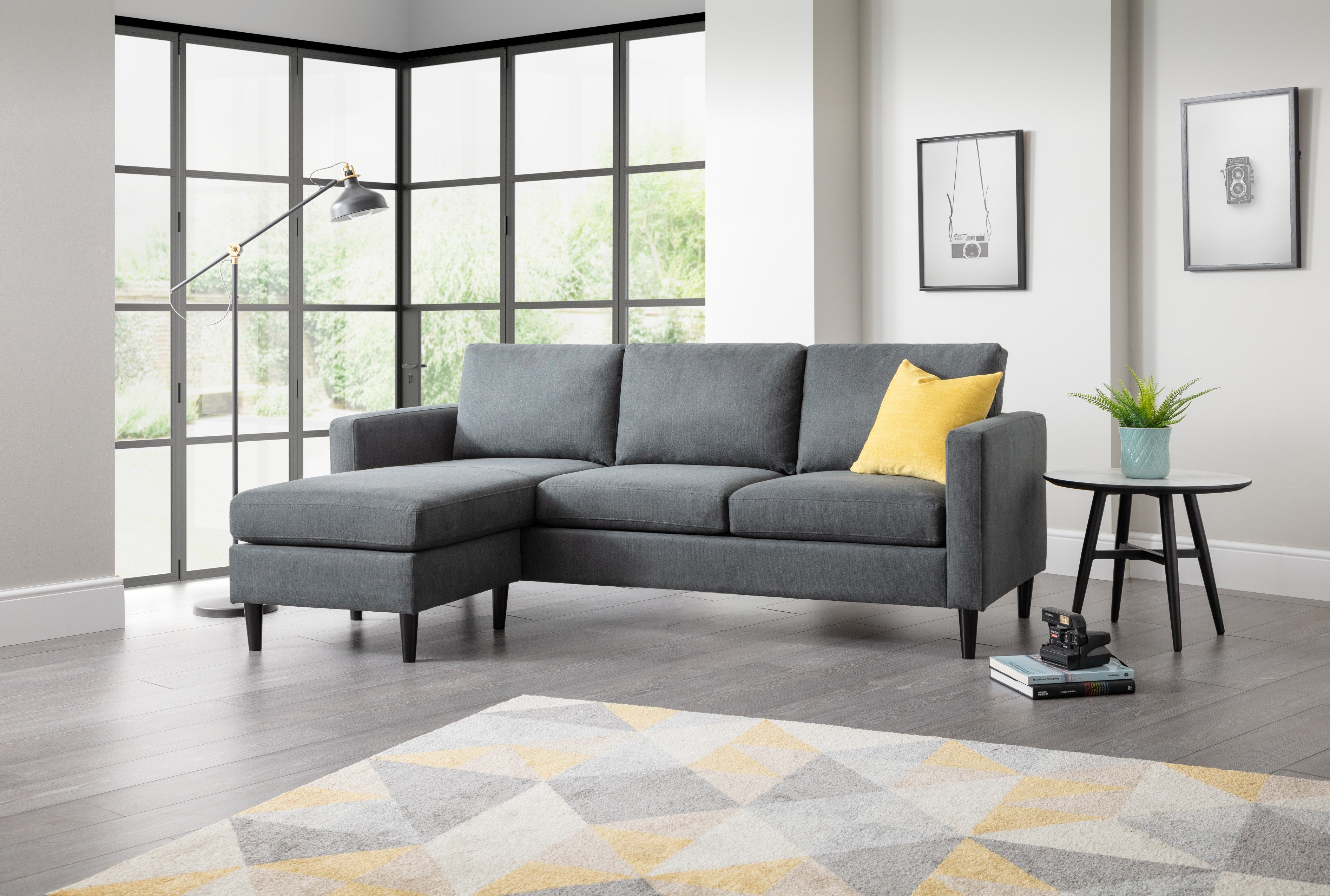 Gray sectional sofa with a yellow pillow in a living room setting.