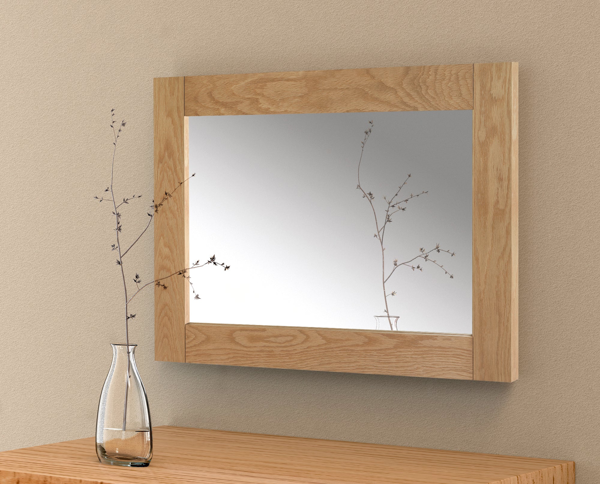 Wooden mirror with a vase of branches on a wooden surface against a beige wall.