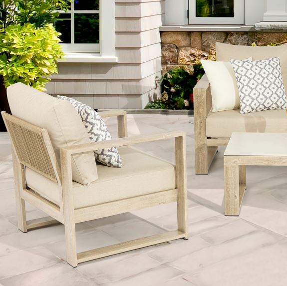 Outdoor patio furniture set with beige chairs and cushions on a stone patio.