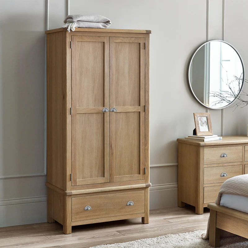 Wooden wardrobe and side table in a bedroom setting with a mirror and bed.