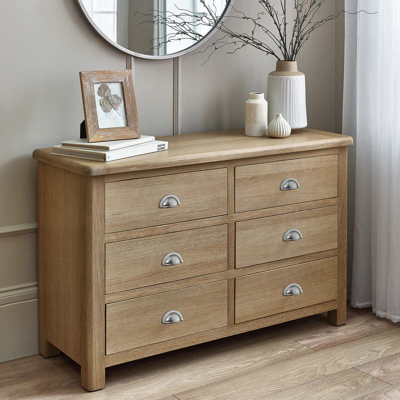 Wooden dresser with four drawers, decorative items on top, and a mirror above.