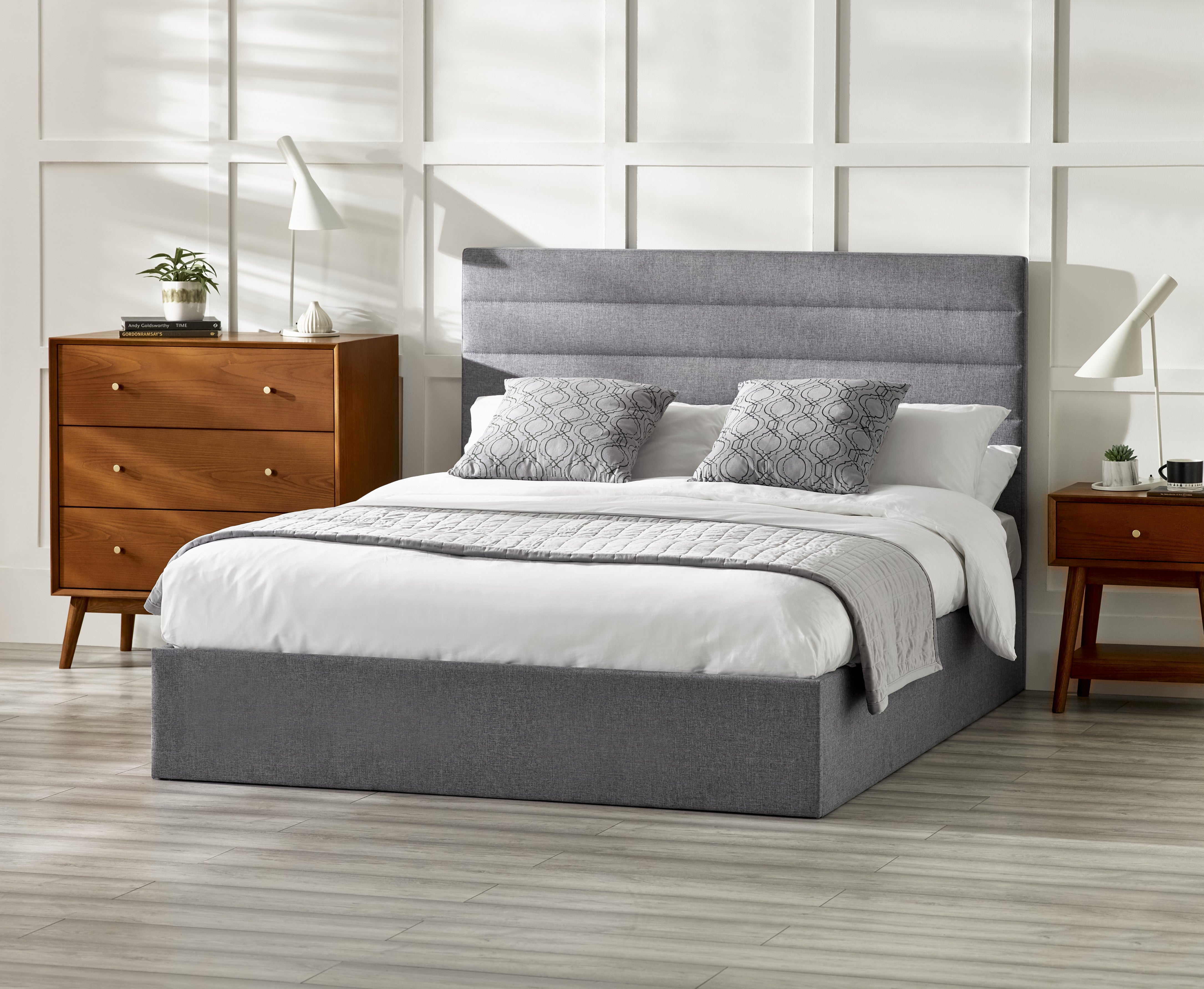 Gray upholstered bed with white bedding in a bedroom setting.