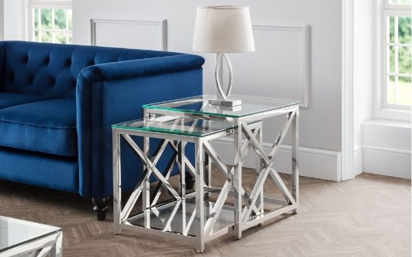 Nesting tables with glass tops in a living room setting with a blue sofa.