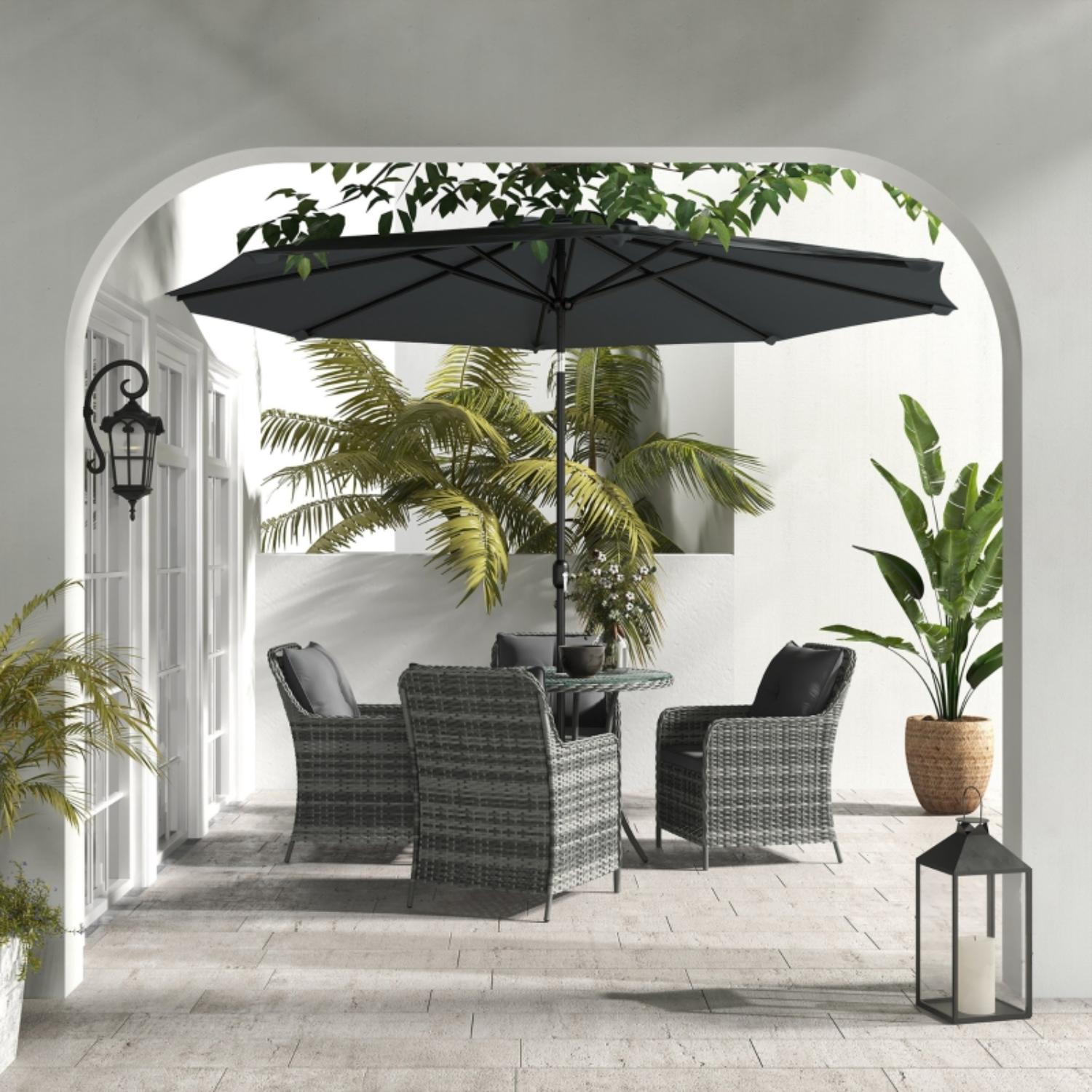 Outdoor patio set with table, chairs, and umbrella on a patio with plants and lanterns.