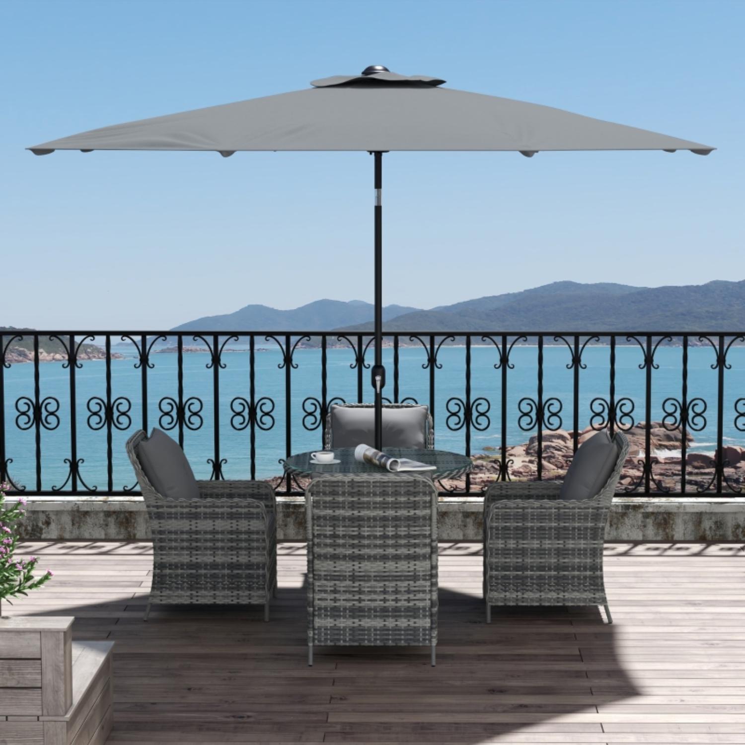 Outdoor patio set with umbrella on a deck overlooking water and mountains