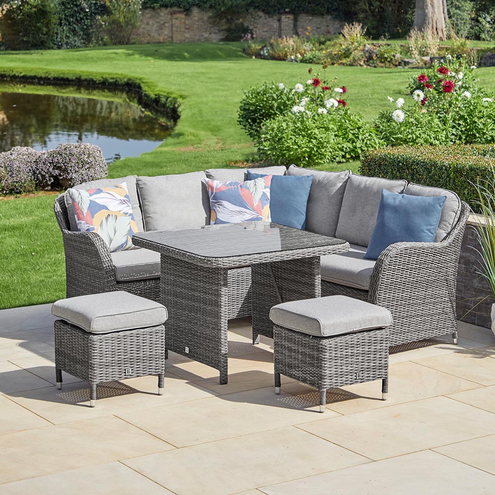 Outdoor patio set with gray cushions and a small table on a stone patio.