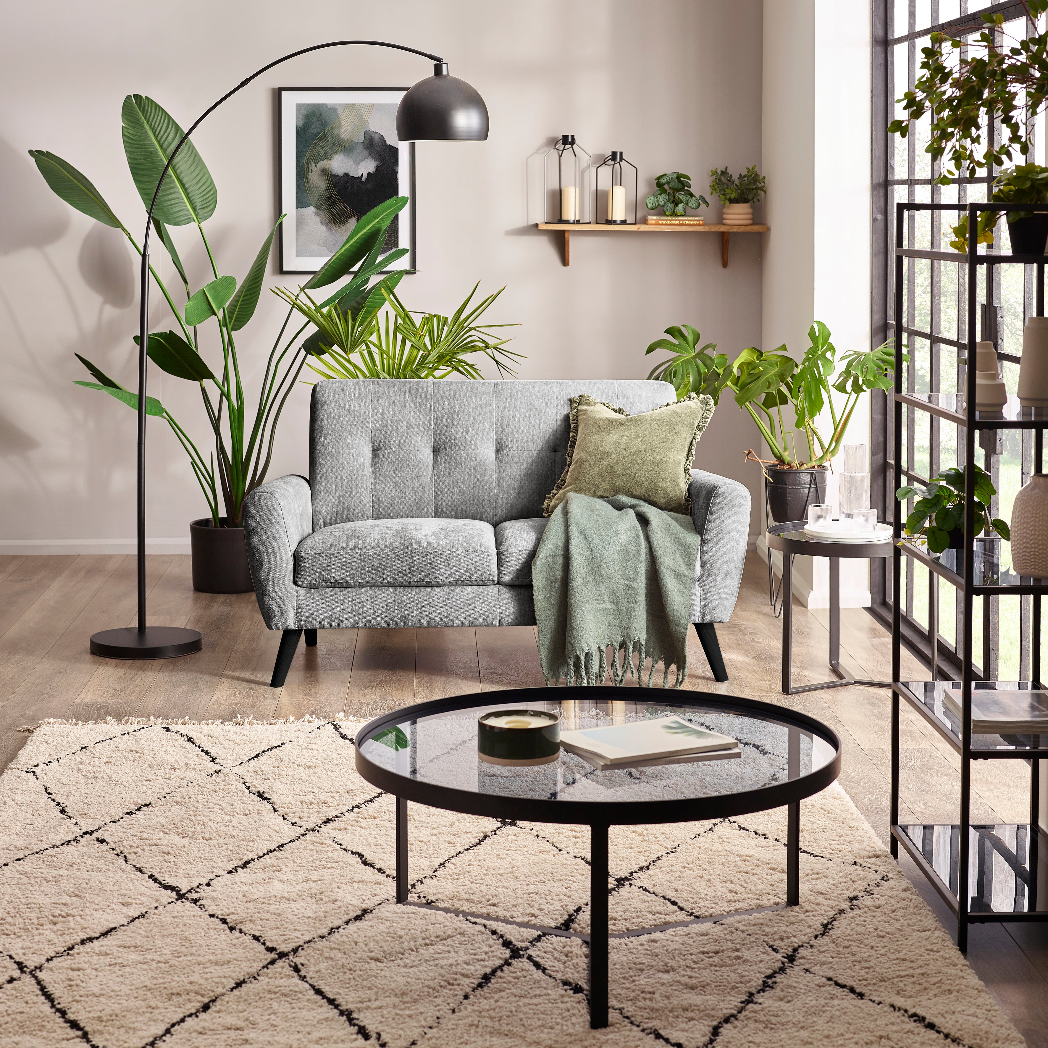 Modern living room with gray sofa, round glass coffee table, and decorative plants.