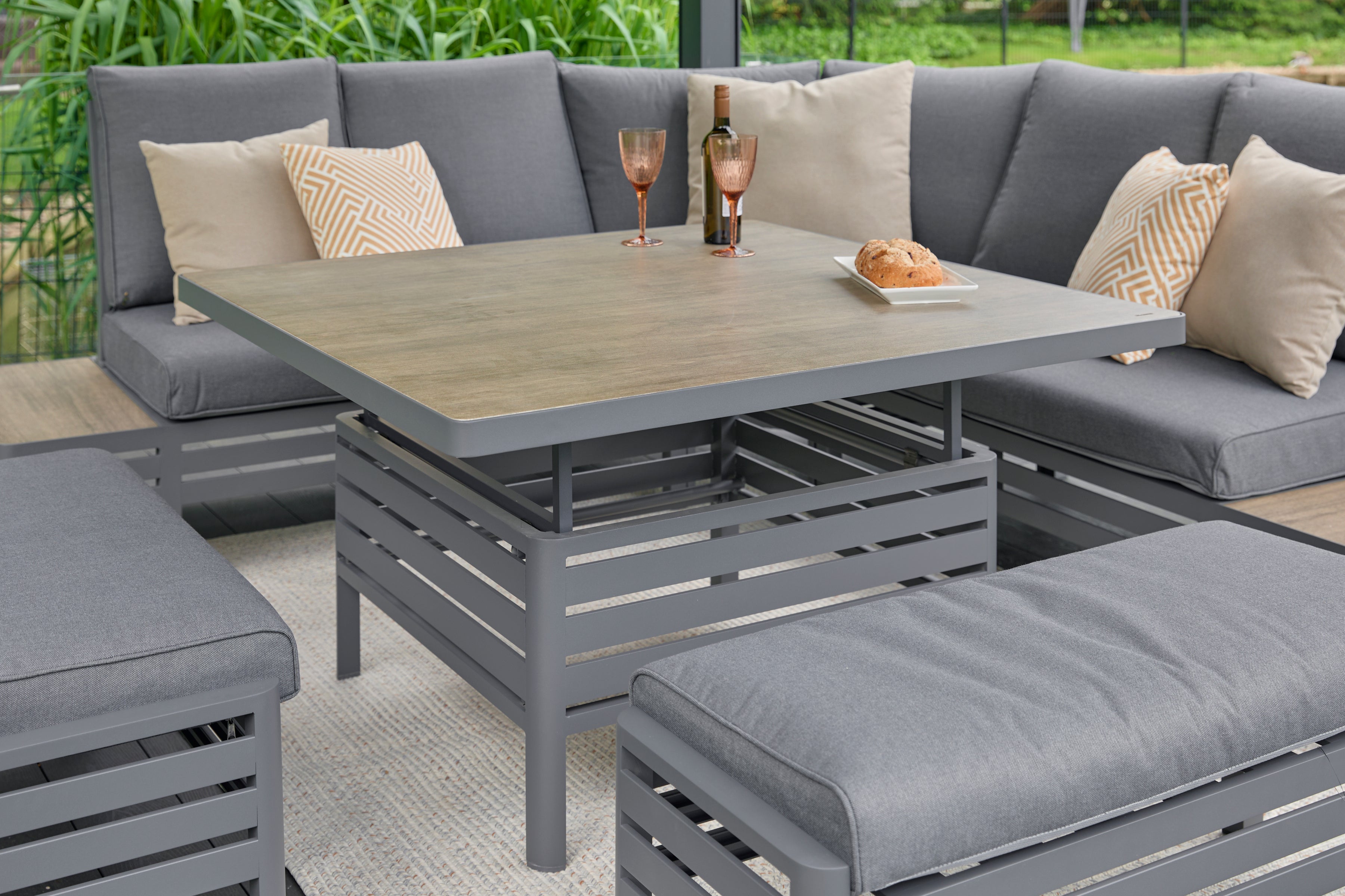 Large modular outdoor dining set with grey cushions and a wood-effect adjustable table