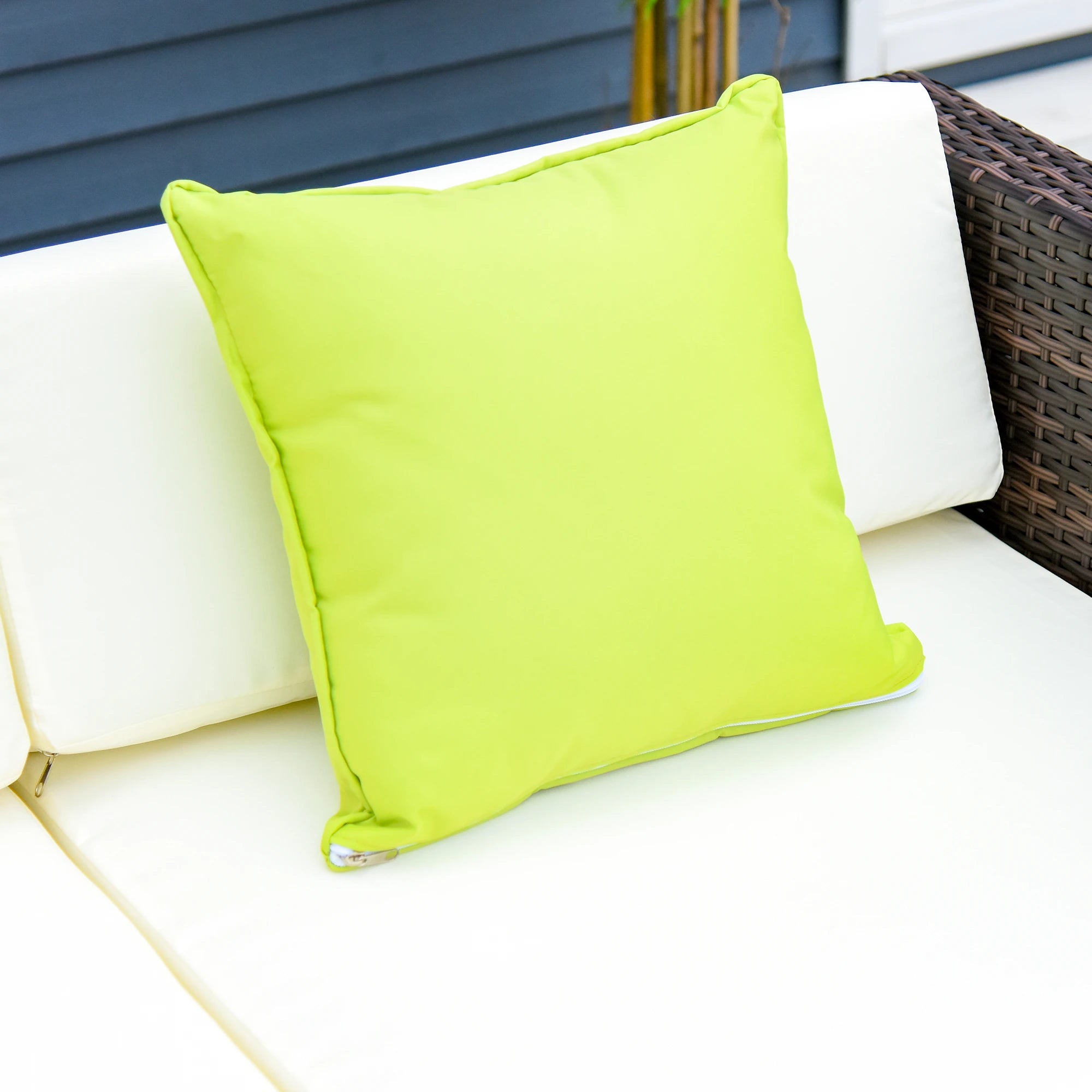 Green pillow on a white outdoor sofa with a blue wall in the background